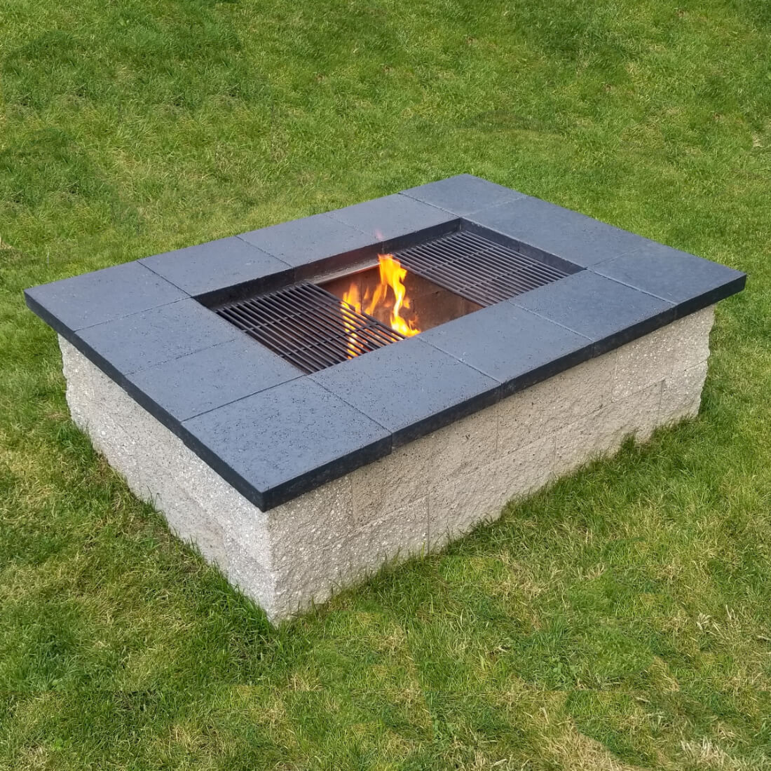 DIY cinder block fire pit grill with a wood fire burning under the grill grates
