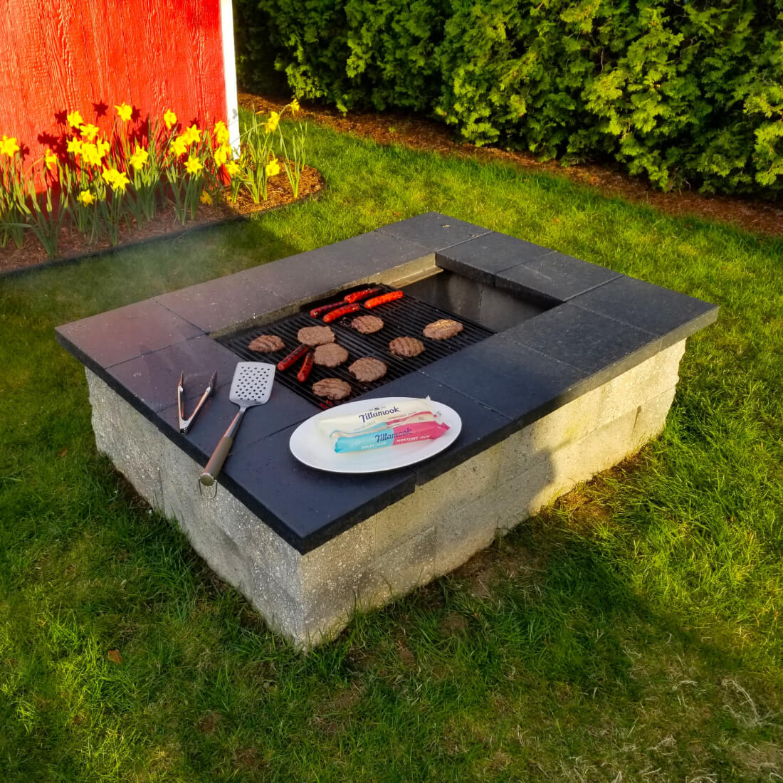 Burgers and hot dogs cooking on a backyard fire pit grill built with the Fire Pit Grill Kit