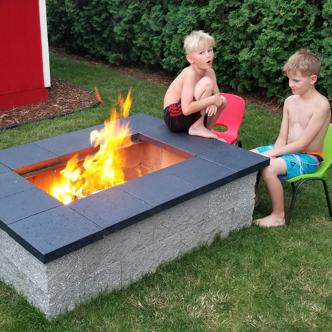 Kids enjoying a campfire in a cinder block fire pit with the grill grates removed
