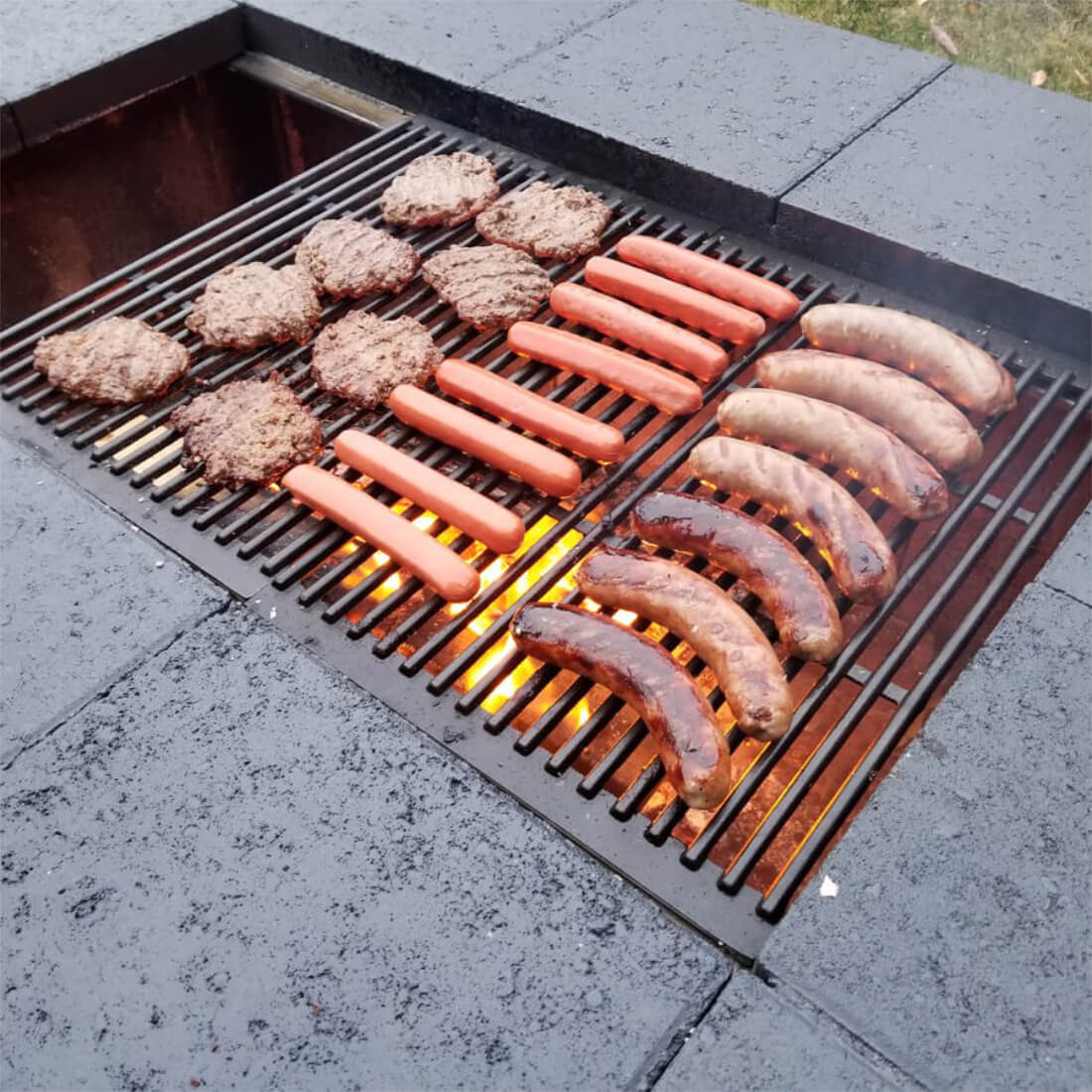 Burgers, brats and hot dogs on the grill grates of a fire pit grill