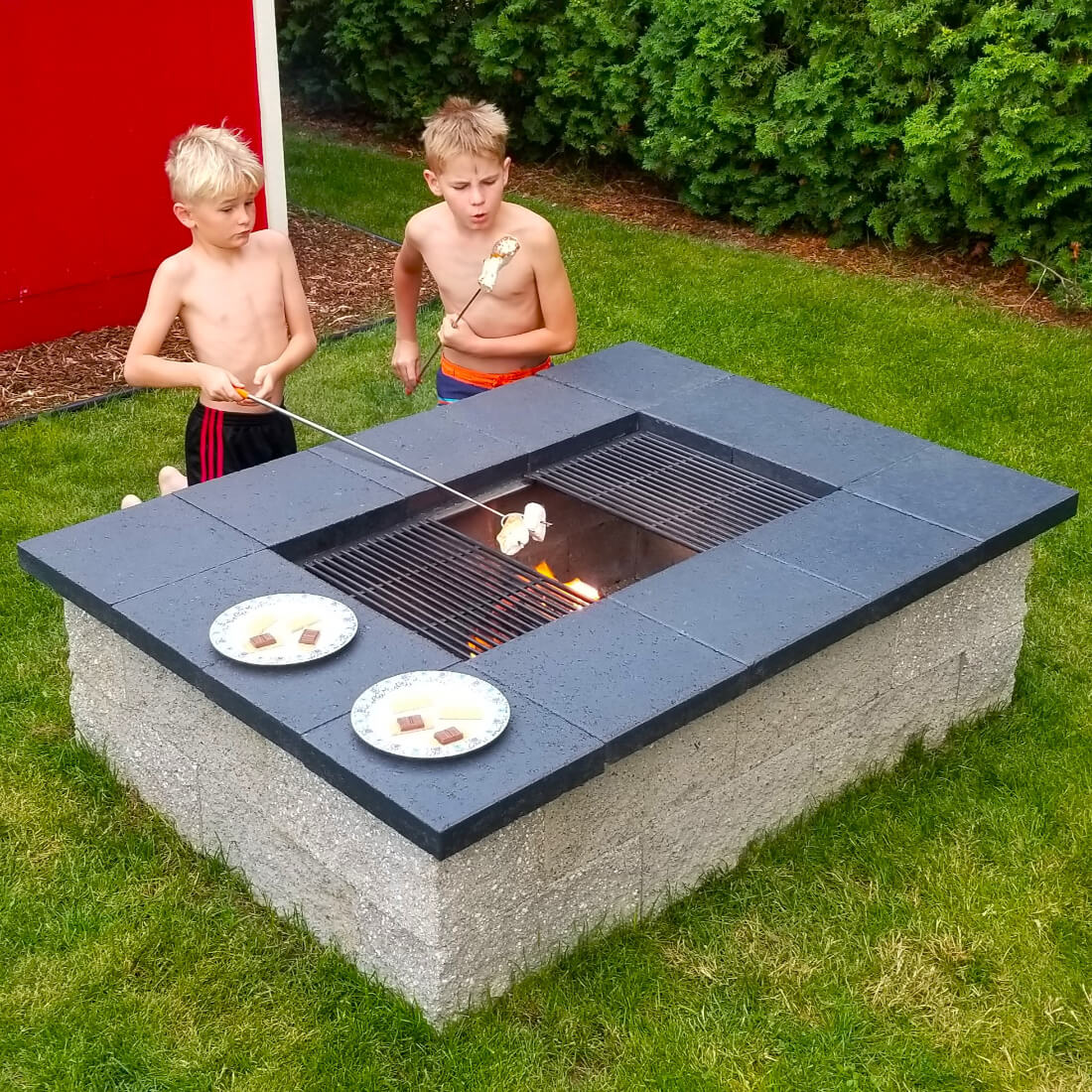 Kids roasting marshmallows over a cinder block fire pit with grill